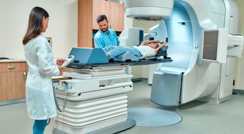 Photogrpagh of a male and female radio oncologist preparing a patient for radiation treatment