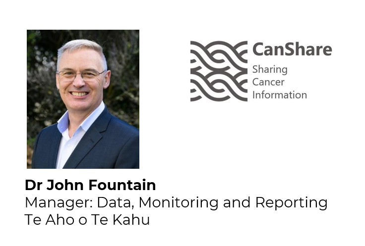 Photpgraph of middle aged man from shoulders up standing outside in front of a hedge. He is smiling and wearing a dark blue suit and white shirt